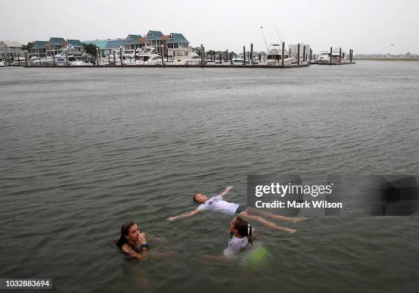 Carson Grace Toomer, Martin-Maine Wrangel, and Elizabeth Claire Toomer, swim in the Intracoastal Waterway as Hurricane Florence approaches the area,...