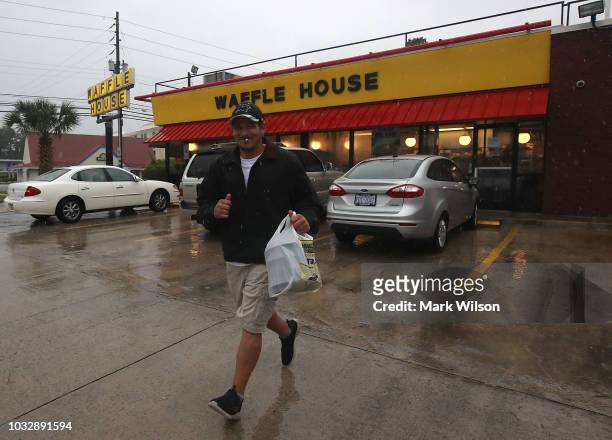 Josh Honeycutt runs to his car after picking up food at Waffle House, as the effects of Hurricane Florence start to hit the area, on September 13,...