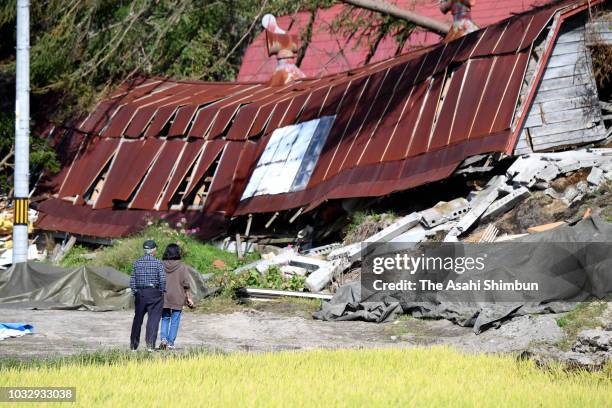 People stand at a destroyed house of their friends a week after the magnitude 6.7 earthquake on September 13, 2018 in Atsuma, Hokkaido, Japan....