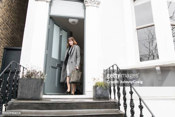 mid adult businesswoman leaving house and closing front door - closing door stock pictures, royalty-free photos & images