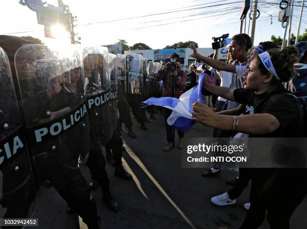 People protest against Nicaraguan President Daniel Ortega's government in front of a line of riot police blocking a street in Managua, on September...