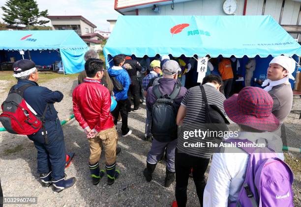 Volunteer workers queue to register a week after the magnitude 6.7 earthquake on September 13, 2018 in Atsuma, Hokkaido, Japan. Concerns are rising...