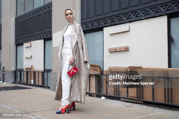 Mademoiselle Meme is seen on the street attending New York Fashion Week SS19 wearing long silver coat with white outfit and red 'Love Me' bag with...