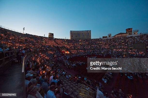 Spectators in the gallery follow the tradition of lighting candles at the start of the performance of 'Aida', on August 8, 2010 in Verona, Italy. The...