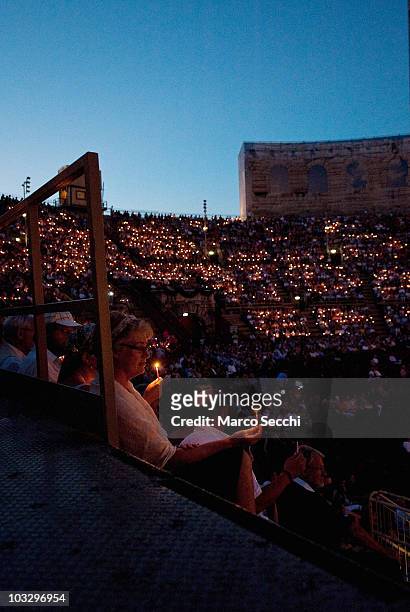 Spectators in the gallery follow the tradition of lighting candles at the start of the performance of 'Aida', on August 8, 2010 in Verona, Italy. The...