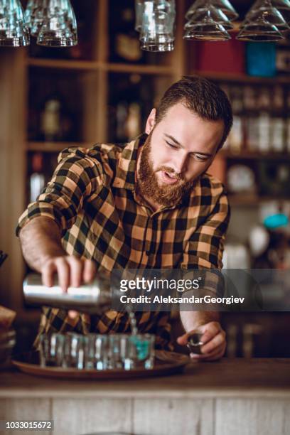 male barista makes cocktail shots during party - hipster barkeeper stock pictures, royalty-free photos & images