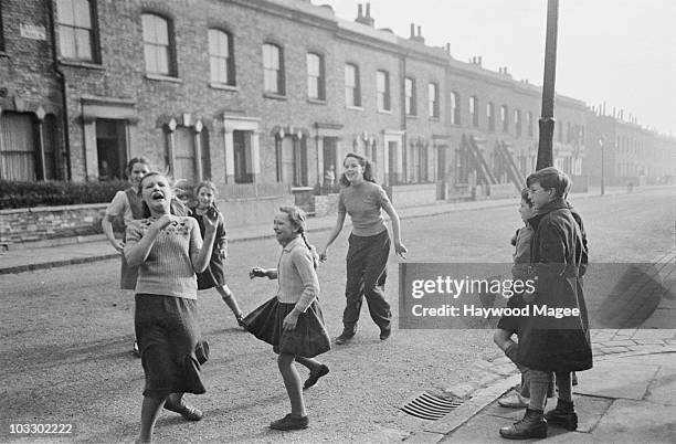 Schoolgirls playing 'He', 'Tig', 'Tag' or 'It' on a London street, April 1950. Original Publication : Picture Post - 5005 - Street Play and Play...