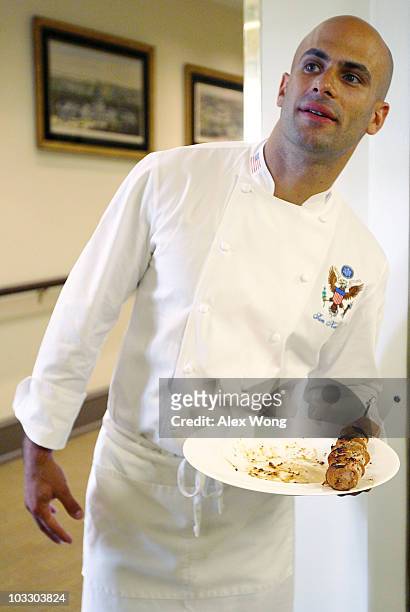 White House chef Sam Kass holds a plate with a seafood kebab sample from the waters of the Gulf of Mexico as members of the New Orleans Saints invite...