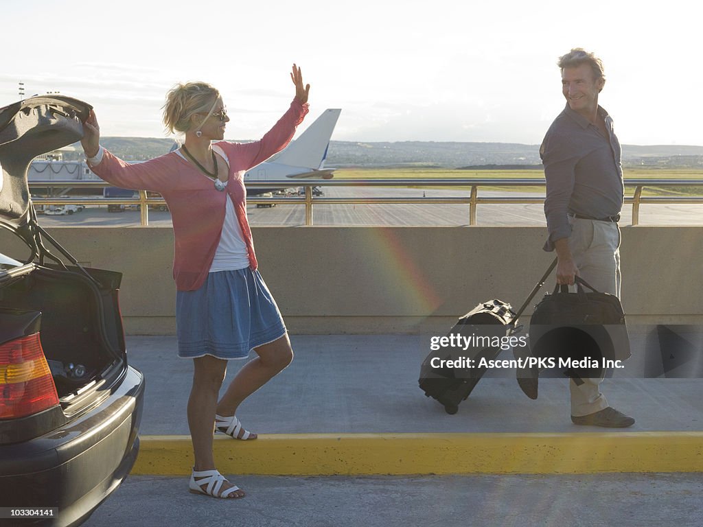 Woman waving goodbye to man at airport