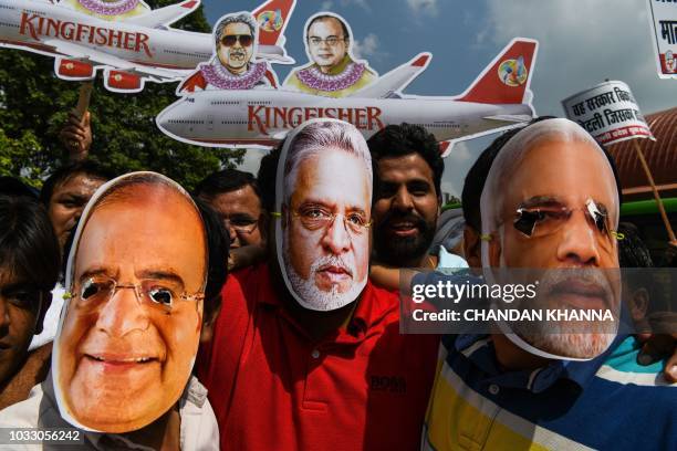 Activists and supporters of the Indian Youth Congress wear masks bearing images of Finance Minister Arun Jaitley , businessman Vijay Mallya and Prime...