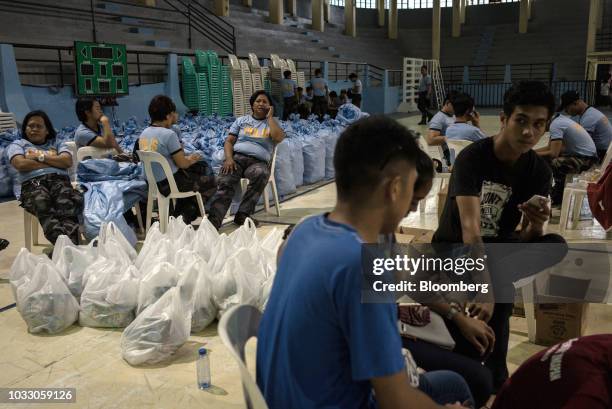 Police and government personnel sit next to bags of relief supplies at a makeshift disaster relief operations center ahead of Typhoon Mangkhut's...