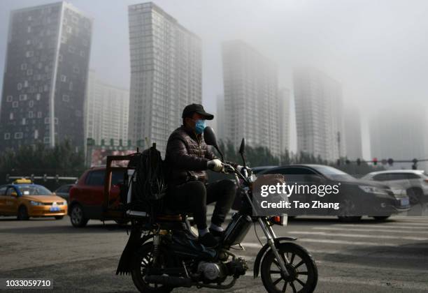 Man rides his motorbike at the Changjiang street during dense fog enveloping Harbin on September 14, 2018 in Harbin, China. The meteorological...