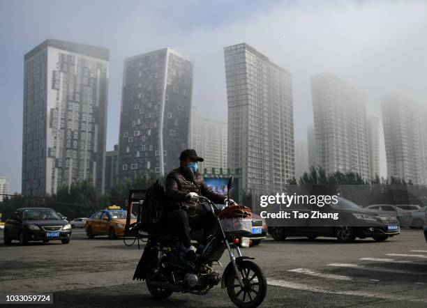 Man rides his motorbike at the Changjiang street during dense fog enveloping Harbin on September 14, 2018 in Harbin, China. The meteorological...