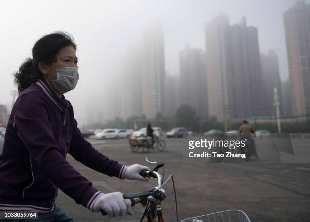 Woman rides her bicycle at the Changjiang street during dense fog enveloping Harbin on September 14, 2018 in Harbin, China. The meteorological...