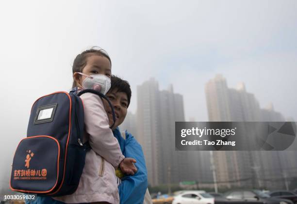 Woman hold her child with mask at the Changjiang street during dense fog enveloping Harbin on September 14, 2018 in Harbin, China. The meteorological...