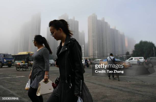 People walk at the Changjiang street during dense fog enveloping Harbin on September 14, 2018 in Harbin, China. The meteorological department issued...