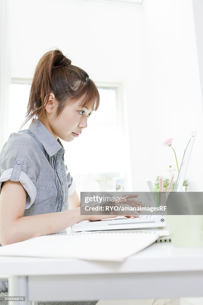 Young woman sitting at a desk and using a laptop