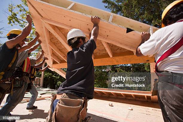 carpenters lifting roofing gable frame at a construction site - collecting wood stock pictures, royalty-free photos & images