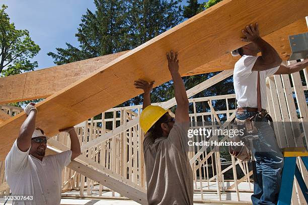 carpenters lifting a laminated beam at a construction site - lifting up sunglasses stock pictures, royalty-free photos & images