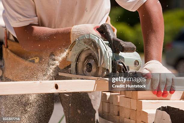 carpenter sawing wall studs at a construction site - segatura foto e immagini stock