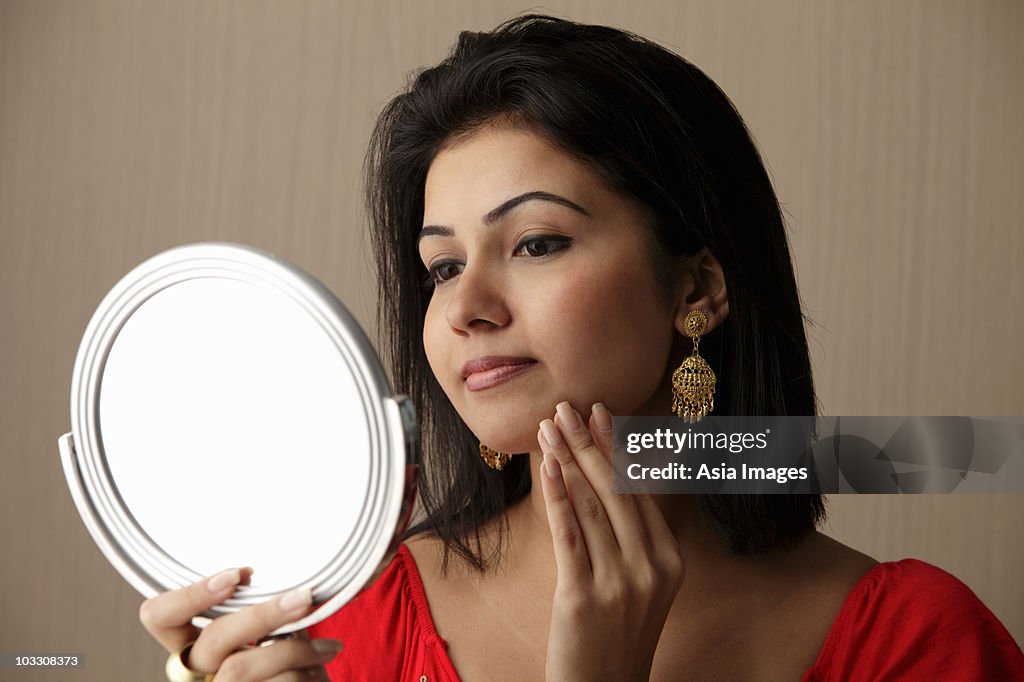 Head shot of woman looking at her face in the mirror