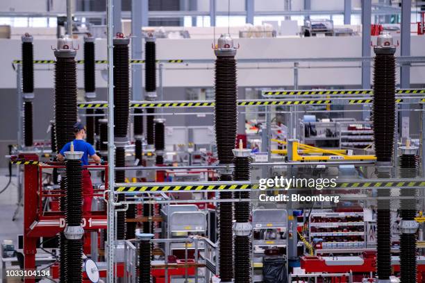 An employee stands on an elevated cherry picker platform while working on the live tank circuit breaker production line inside Siemens AG switchgear...