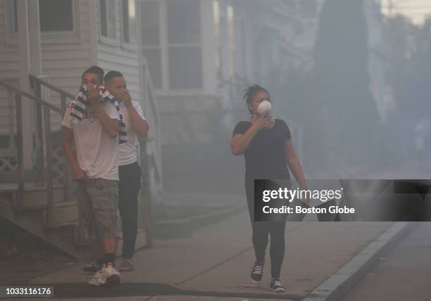 People cover their faces to protect themselves from heavy smoke from a fire on Bowdoin Street in Lawrence, MA on Sep. 13, 2018. More than 60 fires...