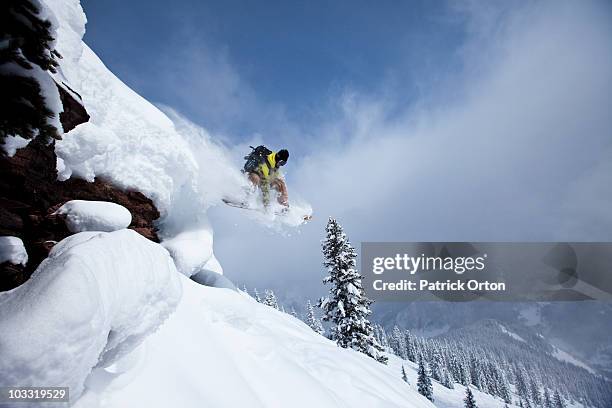 a snowboarder jumps off a cliff into powder in colorado. - exhilaration stock pictures, royalty-free photos & images