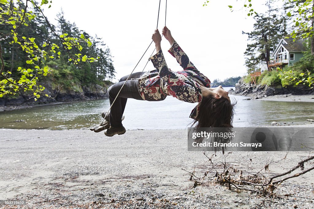 A young woman enjoys a swing hung from a tree near the water's edge of Doe Bay on Orcas Island.
