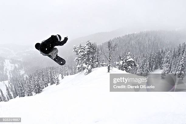 a man on a snowboard flies through the air after hitting a jump. - extreme snowboarding stock pictures, royalty-free photos & images