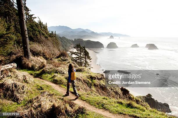 a woman hiking a secluded path along the coastline. - oregon coast stock-fotos und bilder