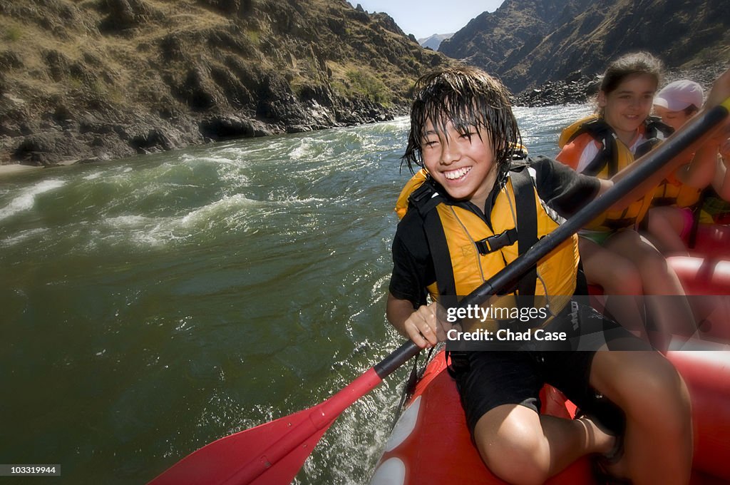 Asian American boy smiling while white water rafting.