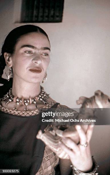 Artist Frida Kahlo poses for a portrait at the home and studio she shares with her husband Diego Rivera, designed by architect Juan O'Gorman circa...