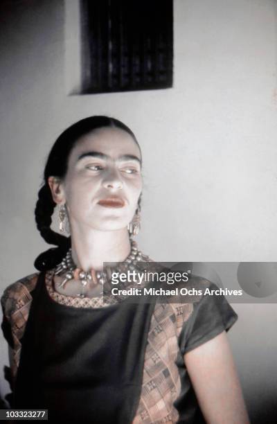 Artist Frida Kahlo poses for a portrait at the home and studio she shares with her husband Diego Rivera, designed by architect Juan O'Gorman circa...