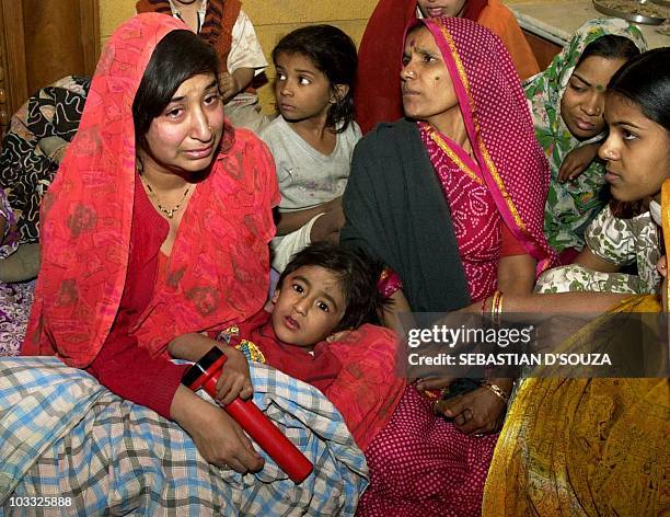 Four-year-old Smirti Sagar, looks-up from her mother's lap 26 January 2001 after she was freed unhurt from under the debris of a four storey...