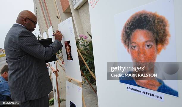 Reverend Dr. Kelvin Calloway, who is from a church close to the crime scenes, leaves a message on photographs set up as a memorial for 10 of the...