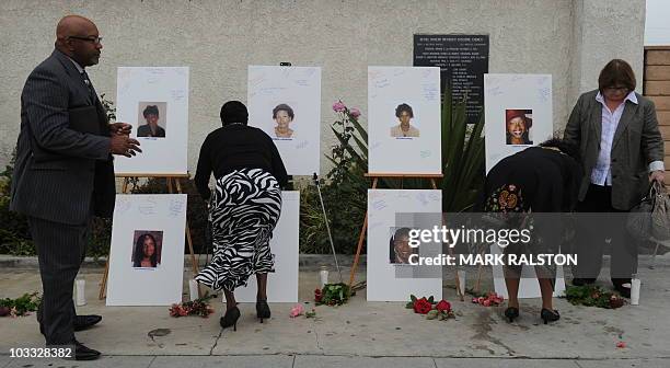 Reverend Dr. Kelvin Calloway , who is from a church close to the crime scenes, and others leave messages on photographs set up as a memorial for 10...