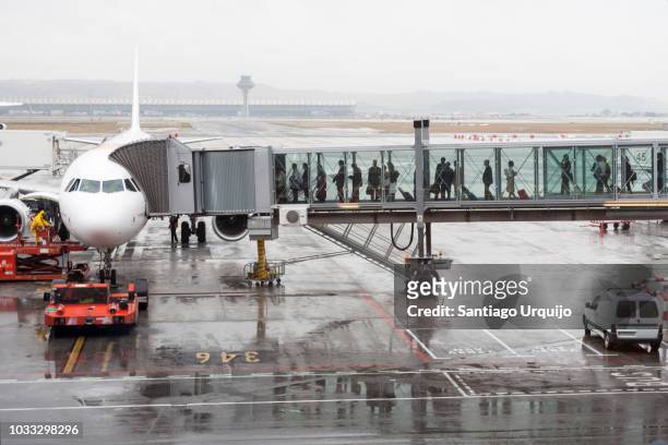 passengers boarding an airplane through a boarding bridge - boarding stockfoto's en -beelden