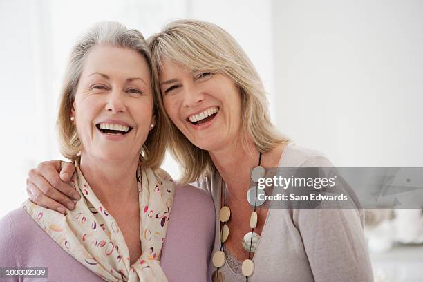 smiling sisters hugging - mature women friends stock pictures, royalty-free photos & images