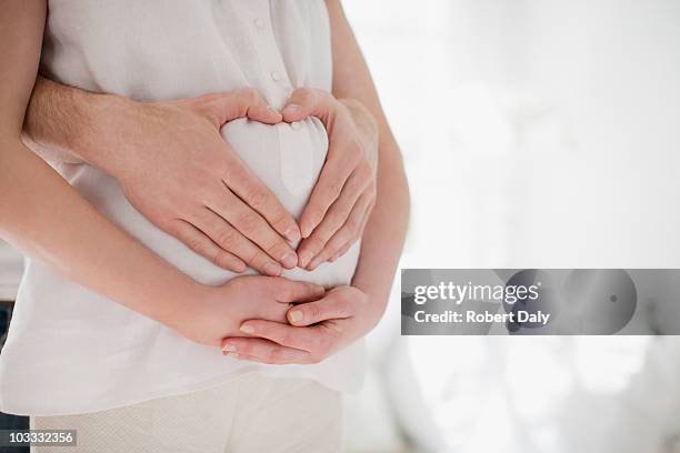 marido formación de forma de corazón en la embarazada wifes estómago - embarazada fotografías e imágenes de stock