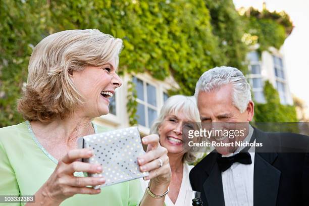 well-dressed senior couple and woman laughing - hombre con grupo de mujeres fotografías e imágenes de stock