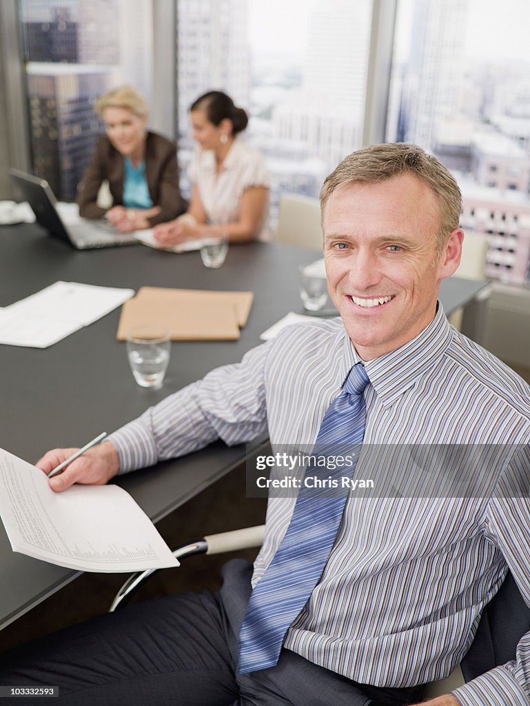 笑顔のビジネスマンが書類を持つコンファレンスルーム
