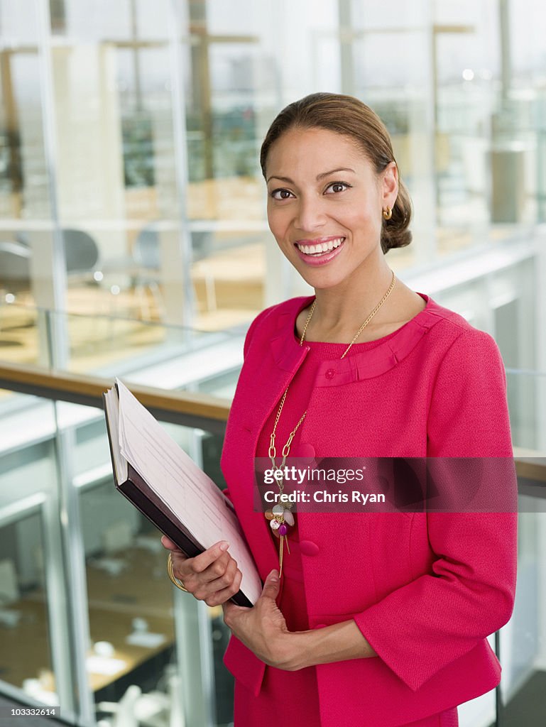 Sorridente Mulher de Negócios segurando a papelada no escritório janela