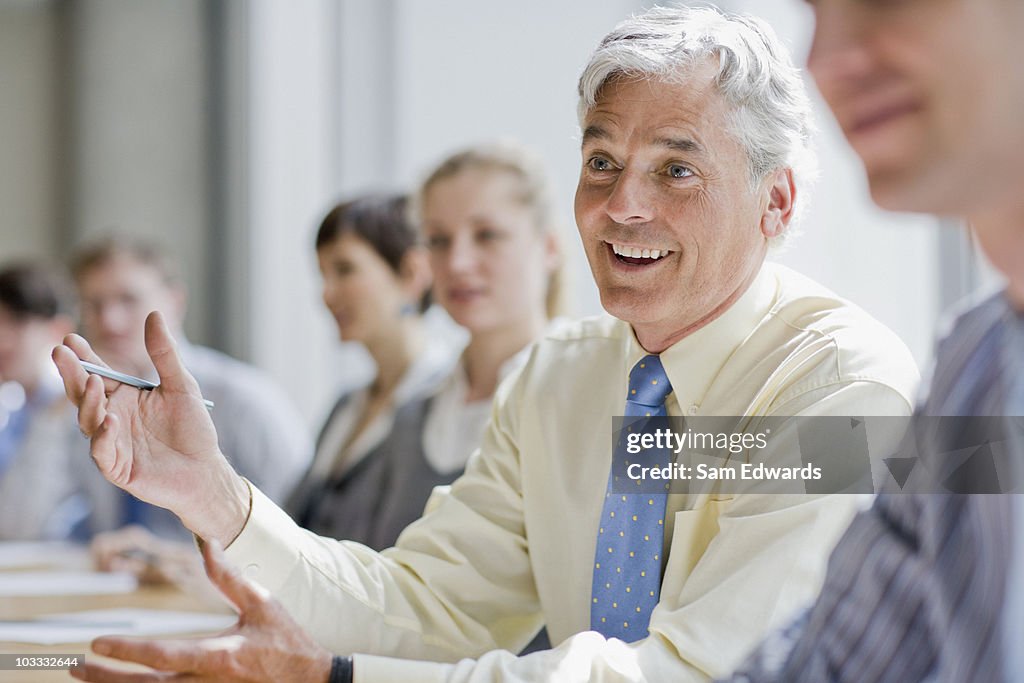 Uomo d'affari sorridente in una riunione di Esprimere a gesti