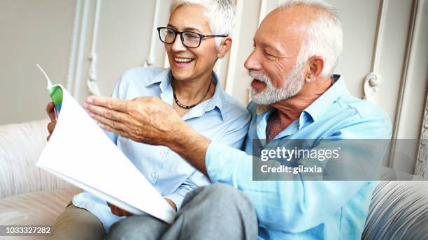 happy senior couple reading a magazine. - brochure stock pictures, royalty-free photos & images