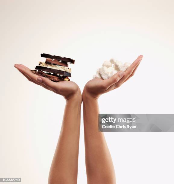 hands cupping chocolate bars and sugar cubes - high arm stock pictures, royalty-free photos & images