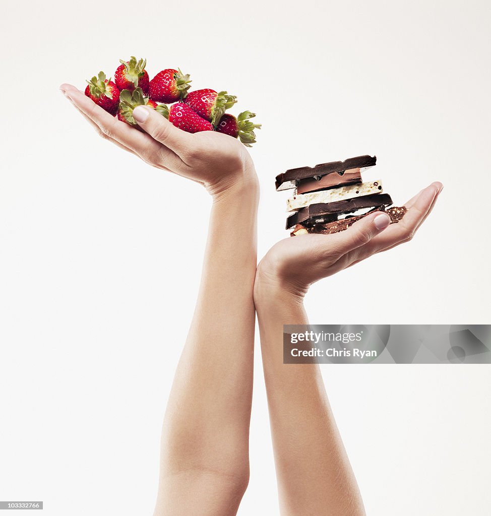 Woman cupping strawberries above chocolate bars