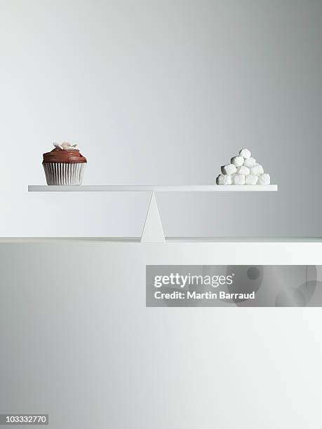 cupcake and stack of sugar cubes balanced on seesaw - excess sugar stock pictures, royalty-free photos & images