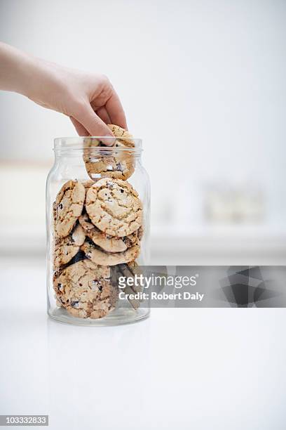 hand erreichen für cookie in krug - cookie jar stock-fotos und bilder