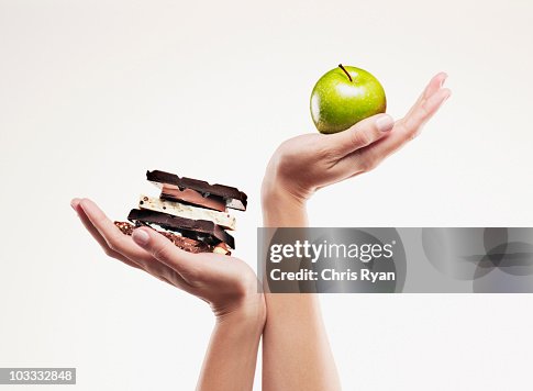 Woman cupping green apple above chocolate bars Woman cupping green apple above chocolate bars
